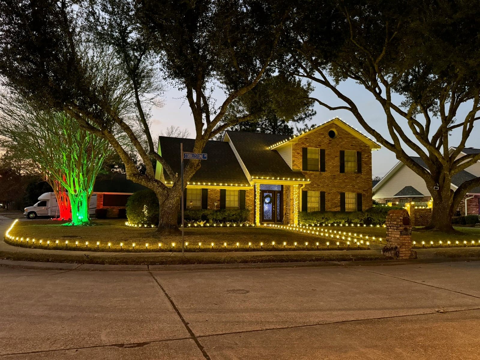 Home with warm white lights lining the lawn, beds and roofline