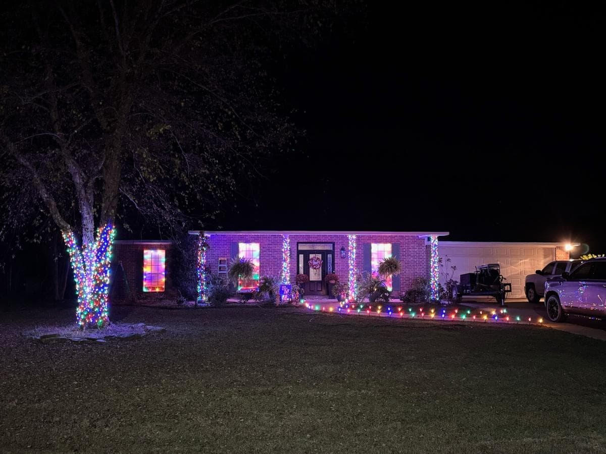 Home with multicolor lights on the tree, columns and driveway